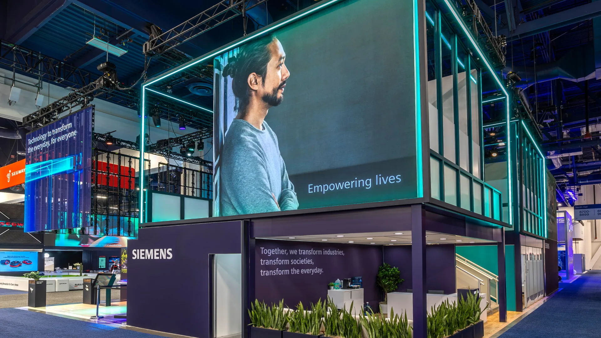 Two-story exhibit with a glowing frame and an LED screen reading Empowering lives