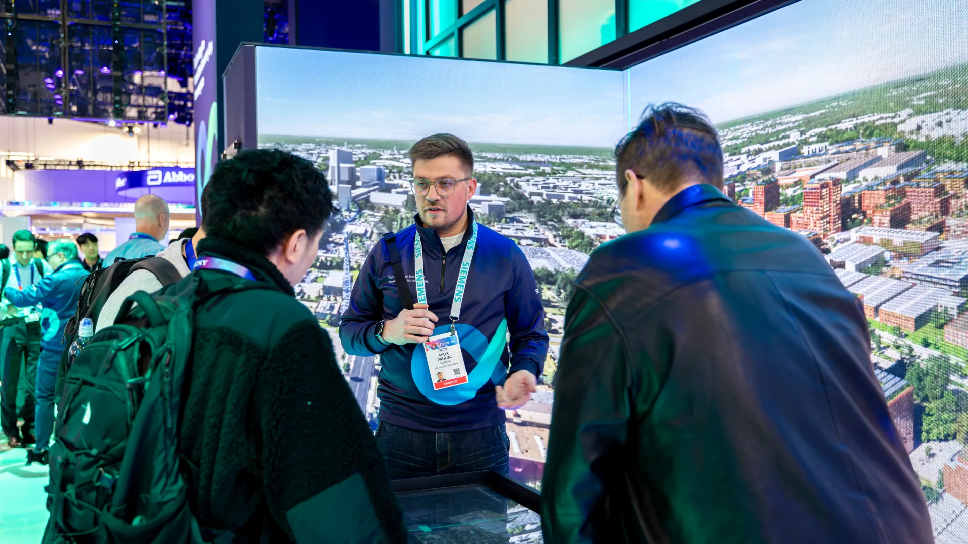 Staff member explains an aerial city view to two attendees at an interactive table