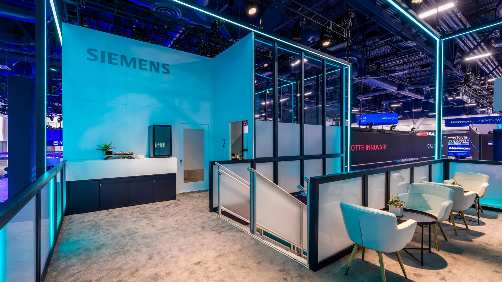 Hospitality lounge with white armchairs, glass railings, and a pale blue Siemens wall