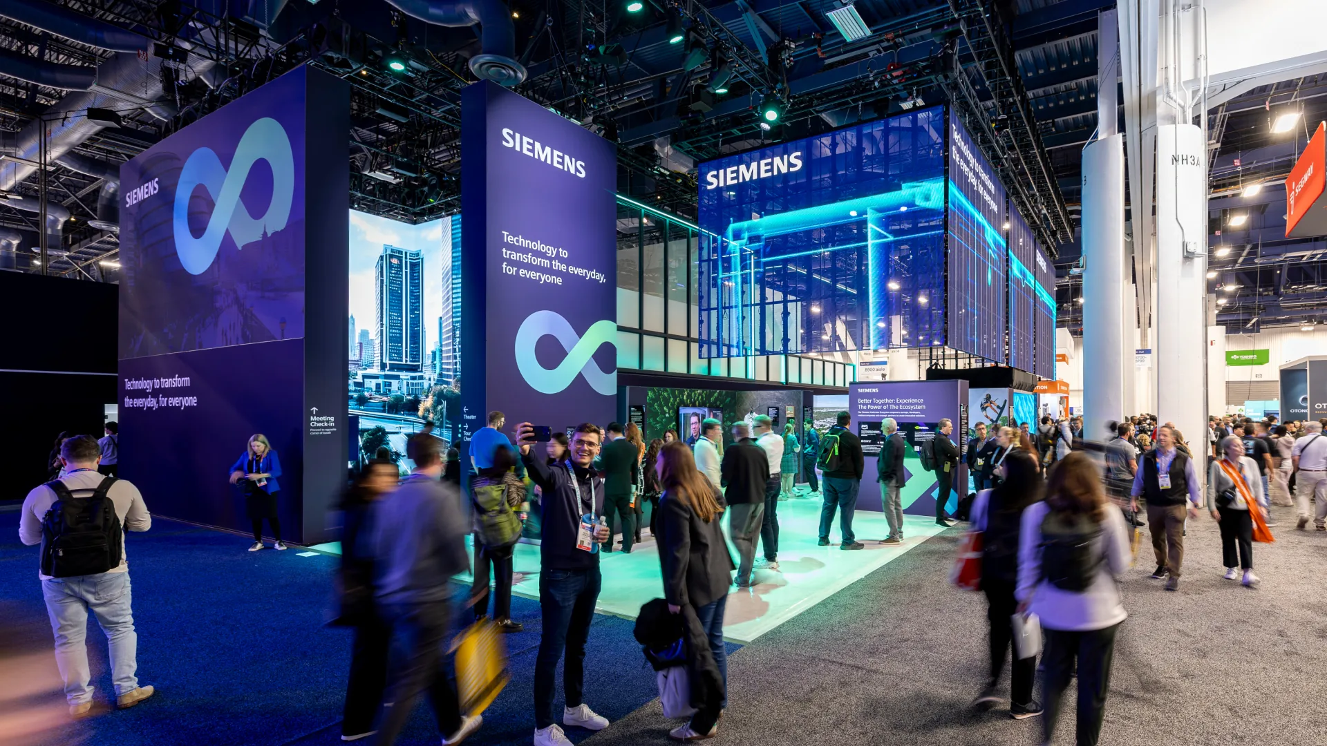 Attendees walk past tall infinity-logo towers at the Siemens CES exhibit