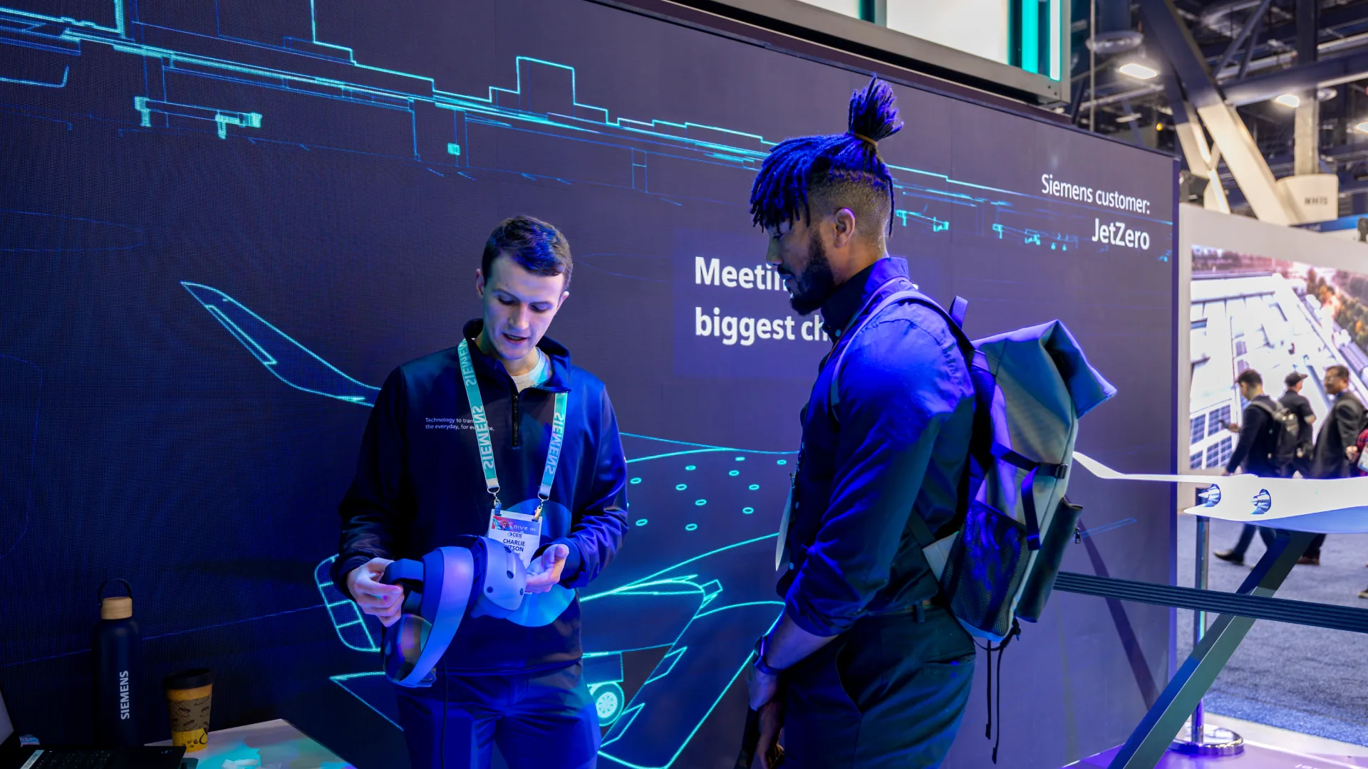 Staff member holds a VR headset while an attendee watches at the JetZero zone