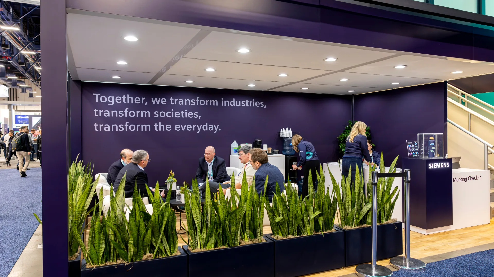 Guests at CES meet in a lounge behind planters near the Meeting Check-in counter
