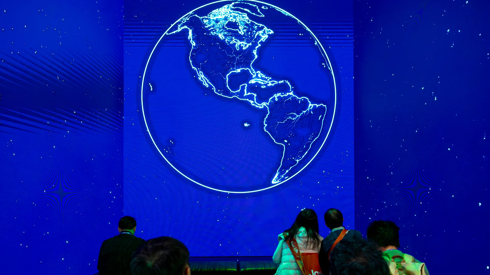 Glowing globe on the blue theater wall as seated visitors watch the show