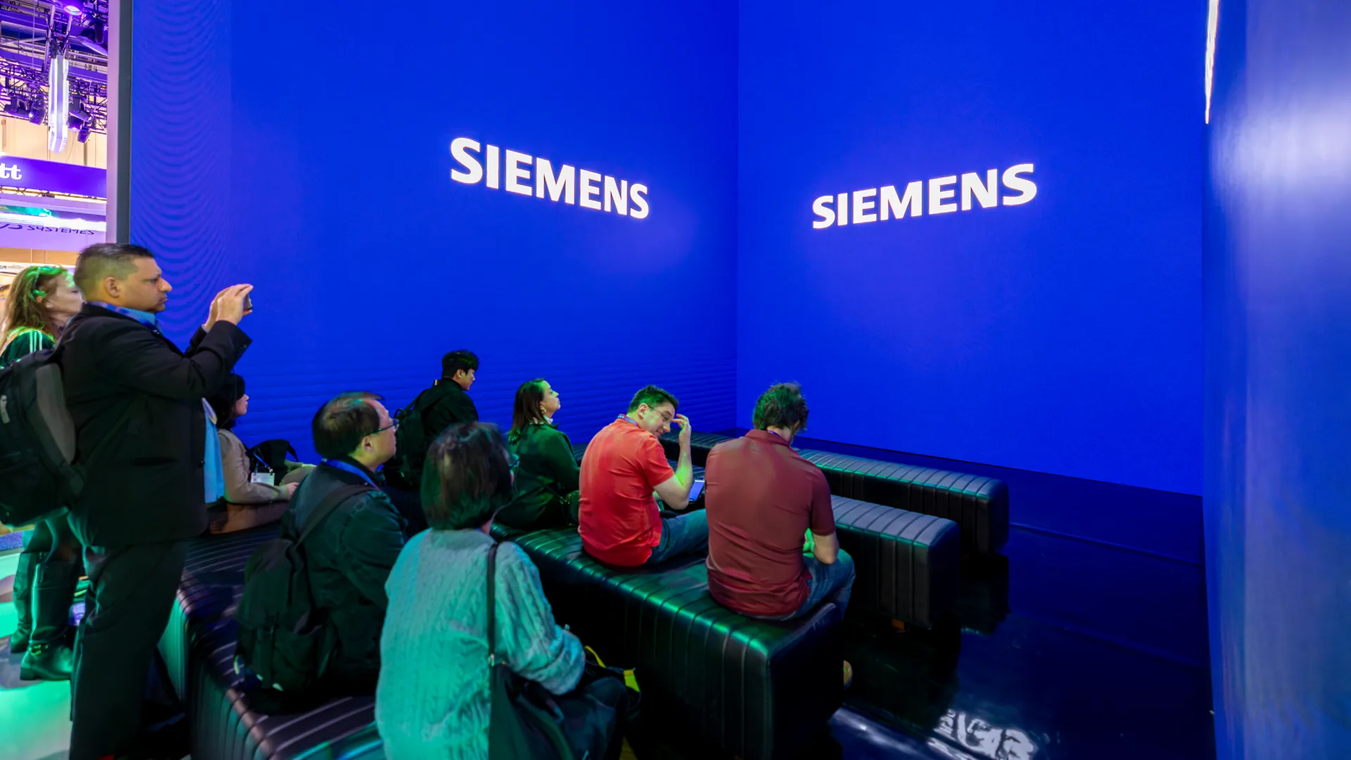 Attendees sit on tiered benches at CES facing a Siemens logo wall