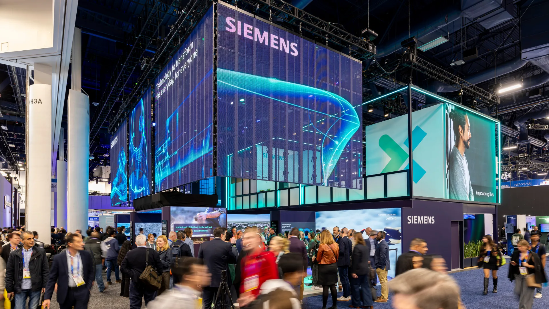 Crowd moves beneath a translucent LED wall displaying the Siemens name