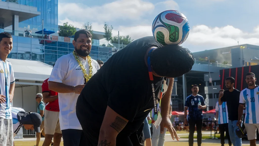 Fan freestyle soccer moment at a Sparks-produced FIFA World Cup 2026 fan experience — a fan heading a FIFA-branded ball while Argentina jersey supporters cheer in the background.