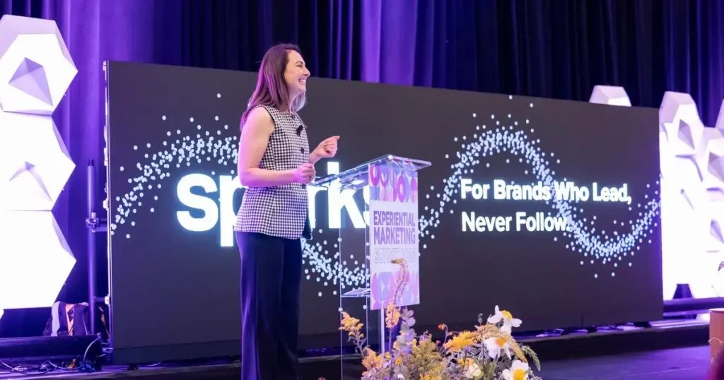 Ashley Paré, founder of The Activator® and panel moderator, opens the 2026 Sparks Executive Forum at the Experiential Marketing Summit podium