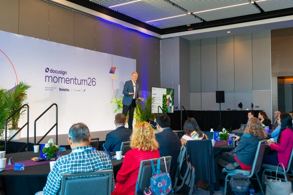 Attendees seated at a Docusign Momentum 2026 breakout session as a presenter speaks in front of a momentum'26 screen.