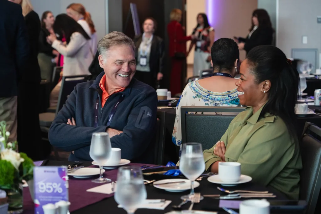 Attendees networking and talking at a table during the Docusign Momentum 2026 Executive Summit.