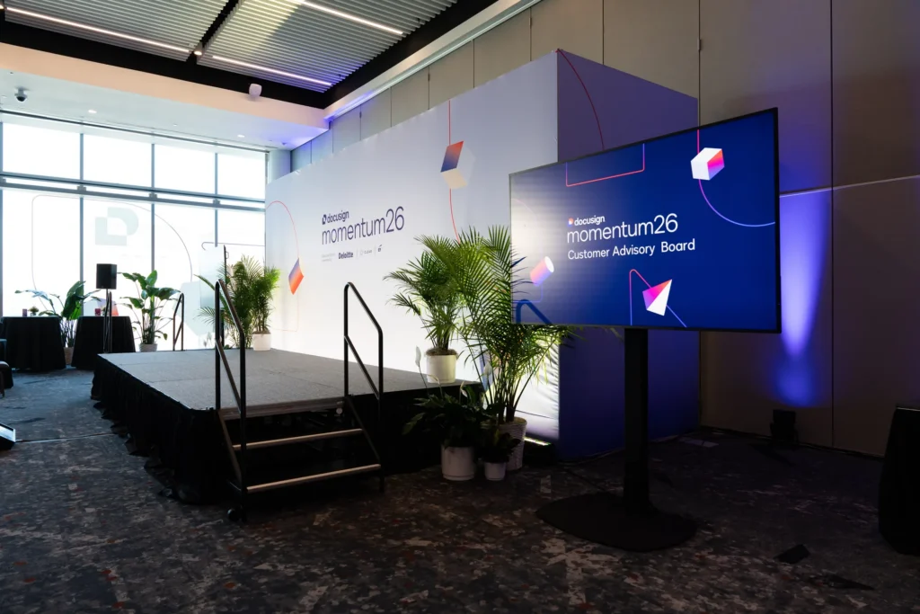 Docusign Momentum 2026 Executive Summit stage with dual LED screens and lounge seating overlooking Manhattan at the Javits Center.