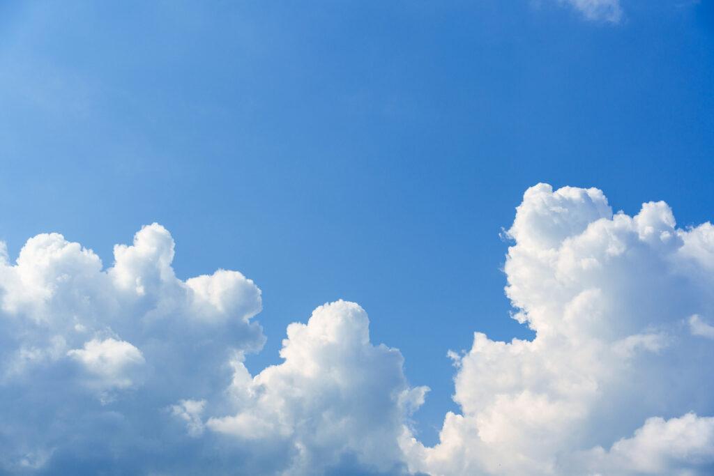 White fluffy cumulus clouds in clear blue sky on sunny day