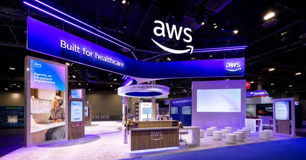AWS 'Built for healthcare' booth at HIMSS 2026 featuring an 'AI-ready data infrastructure' halo, 'Agentic AI for patient engagement' vertical signage, and a wooden welcome desk — Sparks-designed environment at the Venetian Convention & Expo Center in Las Vegas.
