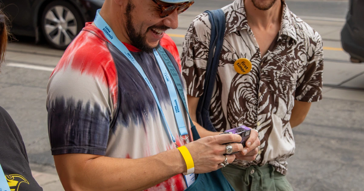 Two Sparks-hosted CEMA Summit 2026 attendees — one wearing a "first timer" pin — sharing photos on a Sparks-branded disposable camera during the Sparks-led walking tour of Toronto's Graffiti Alley.
