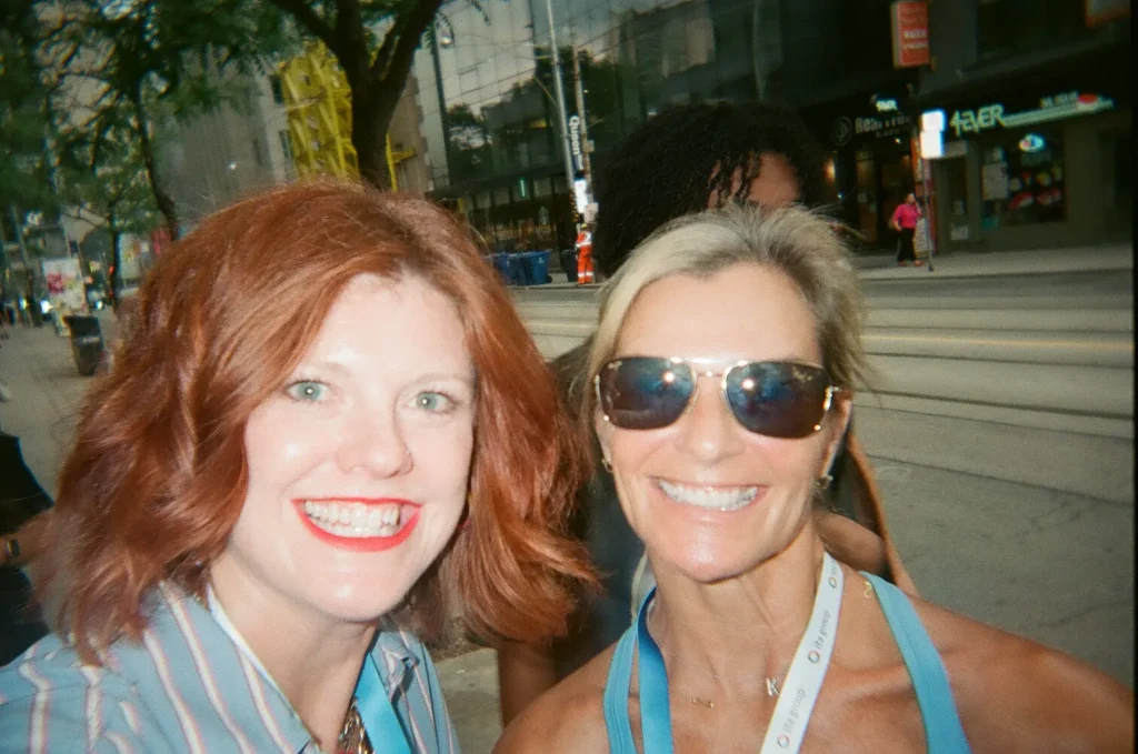 Sparks-hosted CEMA Summit 2026 disposable-camera photo — two CEMA Summit attendees smiling for a portrait on a Toronto street during the Sparks-led Graffiti Alley walking tour.