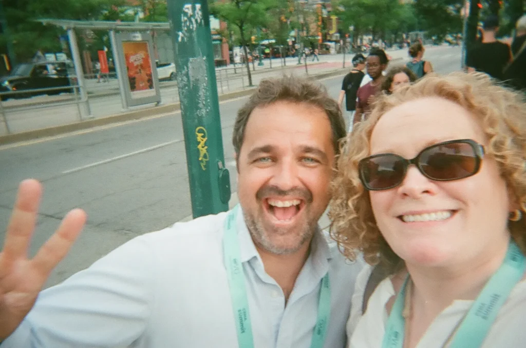 Sparks-hosted CEMA Summit 2026 disposable-camera photo — two CEMA Summit attendees pose with a peace sign for a disposable-camera selfie during the Sparks-led Graffiti Alley walking tour in Toronto.