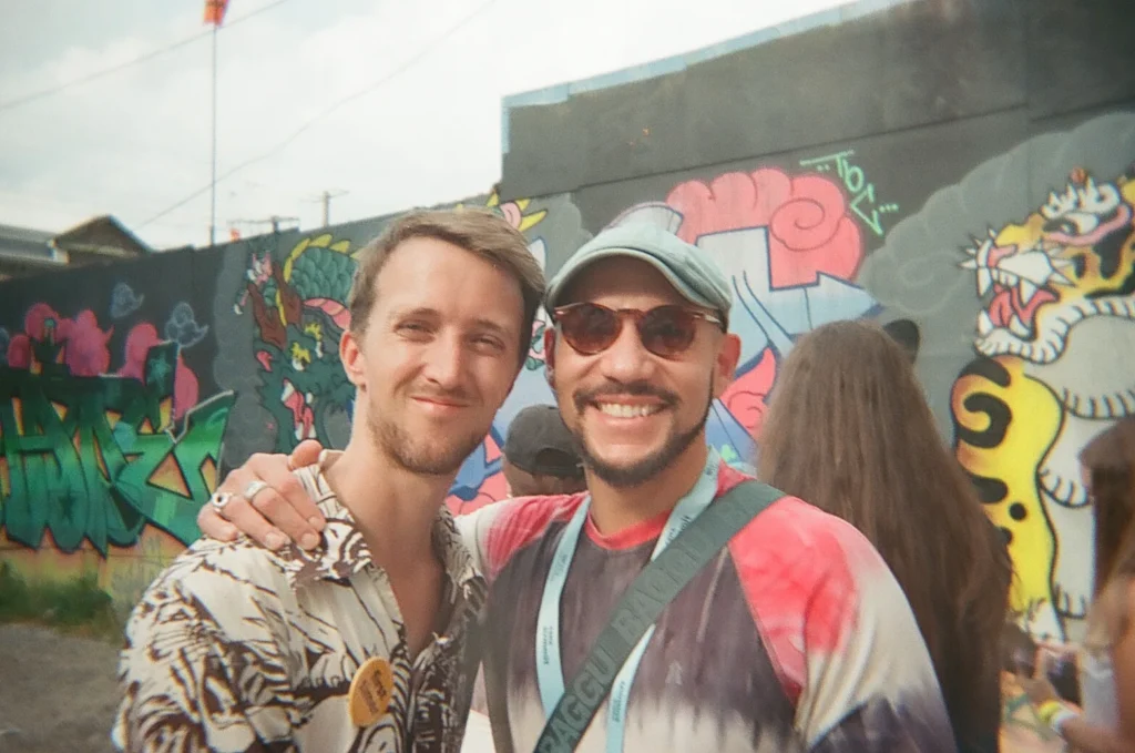 Sparks-hosted CEMA Summit 2026 disposable-camera photo — two CEMA Summit attendees pose together in front of a colorful Graffiti Alley mural during the Sparks-led walking tour in Toronto.