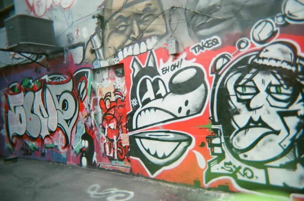 Sparks-hosted CEMA Summit 2026 disposable-camera photo — a cartoon-character graffiti wall in Toronto's Graffiti Alley, captured by a CEMA Summit attendee on the Sparks-led walking tour.