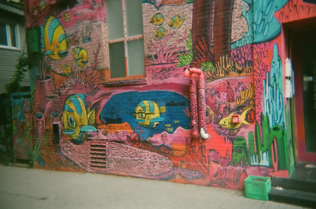 Sparks-hosted CEMA Summit 2026 disposable-camera photo — a wide graffiti-covered wall in Toronto's Graffiti Alley, captured on the Sparks-led CEMA Summit walking tour.