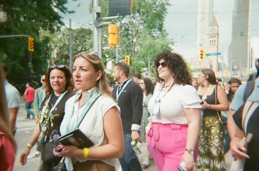 Sparks-hosted CEMA Summit 2026 disposable-camera photo — CEMA Summit attendees walking through downtown Toronto with a church spire in the distance during the Sparks-led Graffiti Alley walking tour.