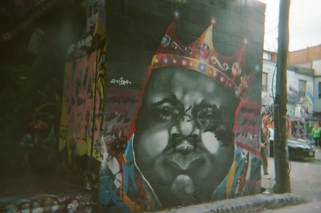 Sparks-hosted CEMA Summit 2026 disposable-camera photo — a large blue-and-gold king portrait mural in Toronto's Graffiti Alley, captured by a CEMA Summit attendee on the Sparks-led walking tour.