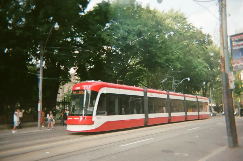 Sparks-hosted CEMA Summit 2026 disposable-camera photo — a red Toronto TTC streetcar passing on a downtown street, taken by a CEMA Summit attendee on the Sparks-led Graffiti Alley walking tour.