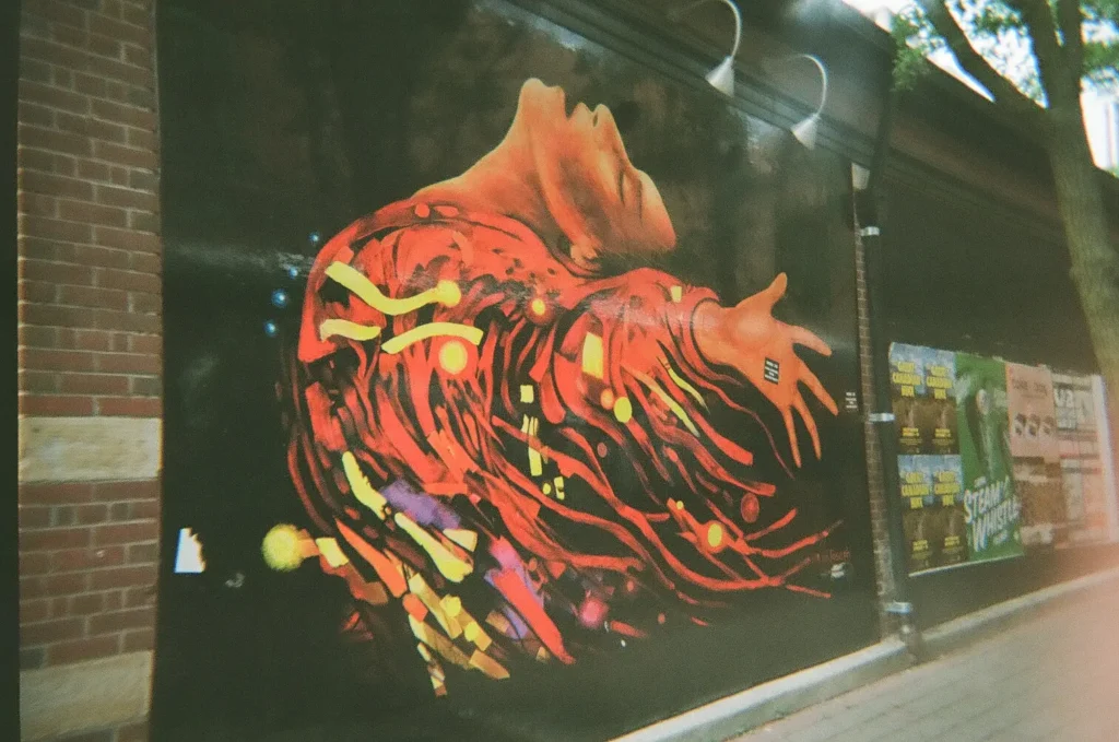 Sparks-hosted CEMA Summit 2026 disposable-camera photo — a flame-hair female-face mural in Toronto's Graffiti Alley, captured by a CEMA Summit attendee on the Sparks-led walking tour.