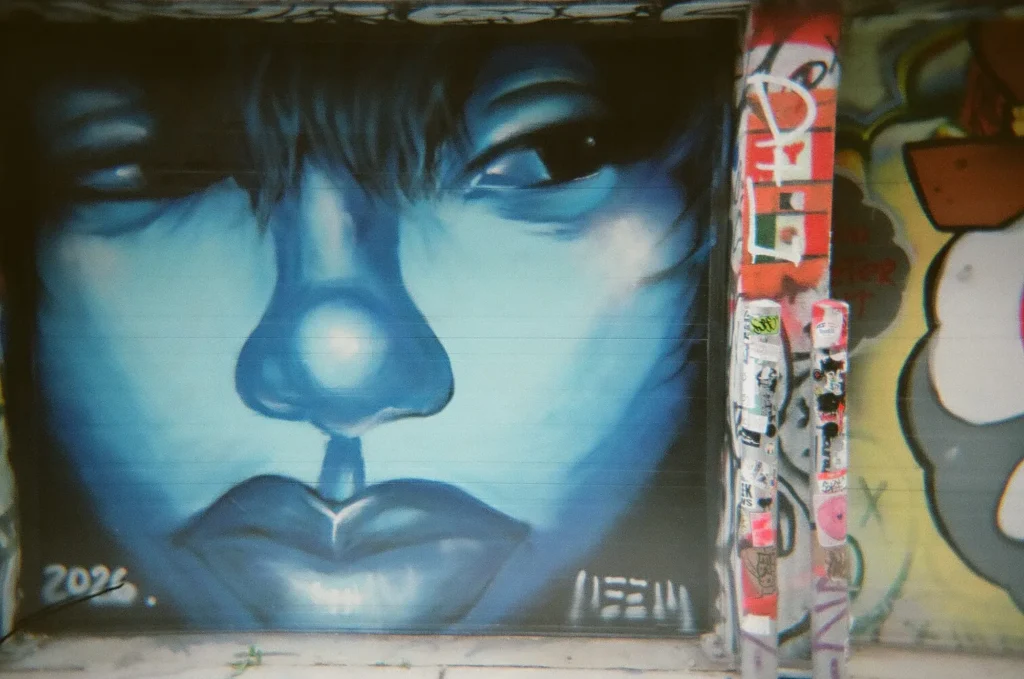 Sparks-hosted CEMA Summit 2026 disposable-camera photo — a striking blue face-portrait mural dated 2026 in Toronto's Graffiti Alley, captured by a CEMA Summit attendee on the Sparks-led walking tour.