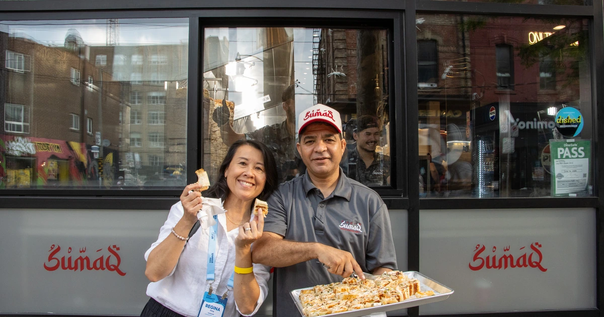 A Sparks-hosted CEMA Summit 2026 attendee samples food from the owner of Sumaq — a Peruvian restaurant in Toronto — during a stop on the Sparks-led Graffiti Alley walking tour.