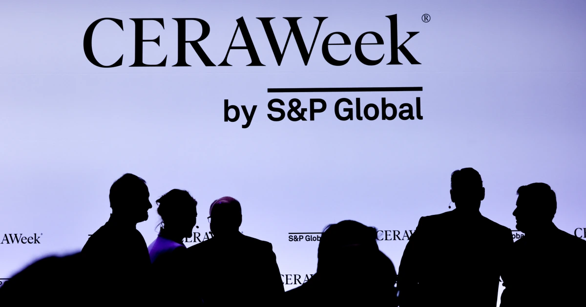 Silhouetted global energy executives networking in front of the massive Sparks-produced CERAWeek by S&P Global backlit signage at CERAWeek 2026 in Houston — the 44th annual conference by S&P Global drawing more than 10,000 delegates from 90 countries.