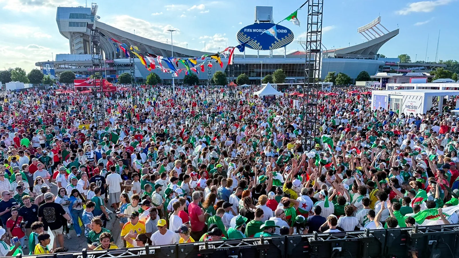 A massive crowd of Mexico fans gathers under the canopy of 48 competing-nation flags Sparks produced at the Stadium Fan Experience Town Square outside Arrowhead Stadium (GEHA Field) at the FIFA World Cup 2026 Kansas City host city.