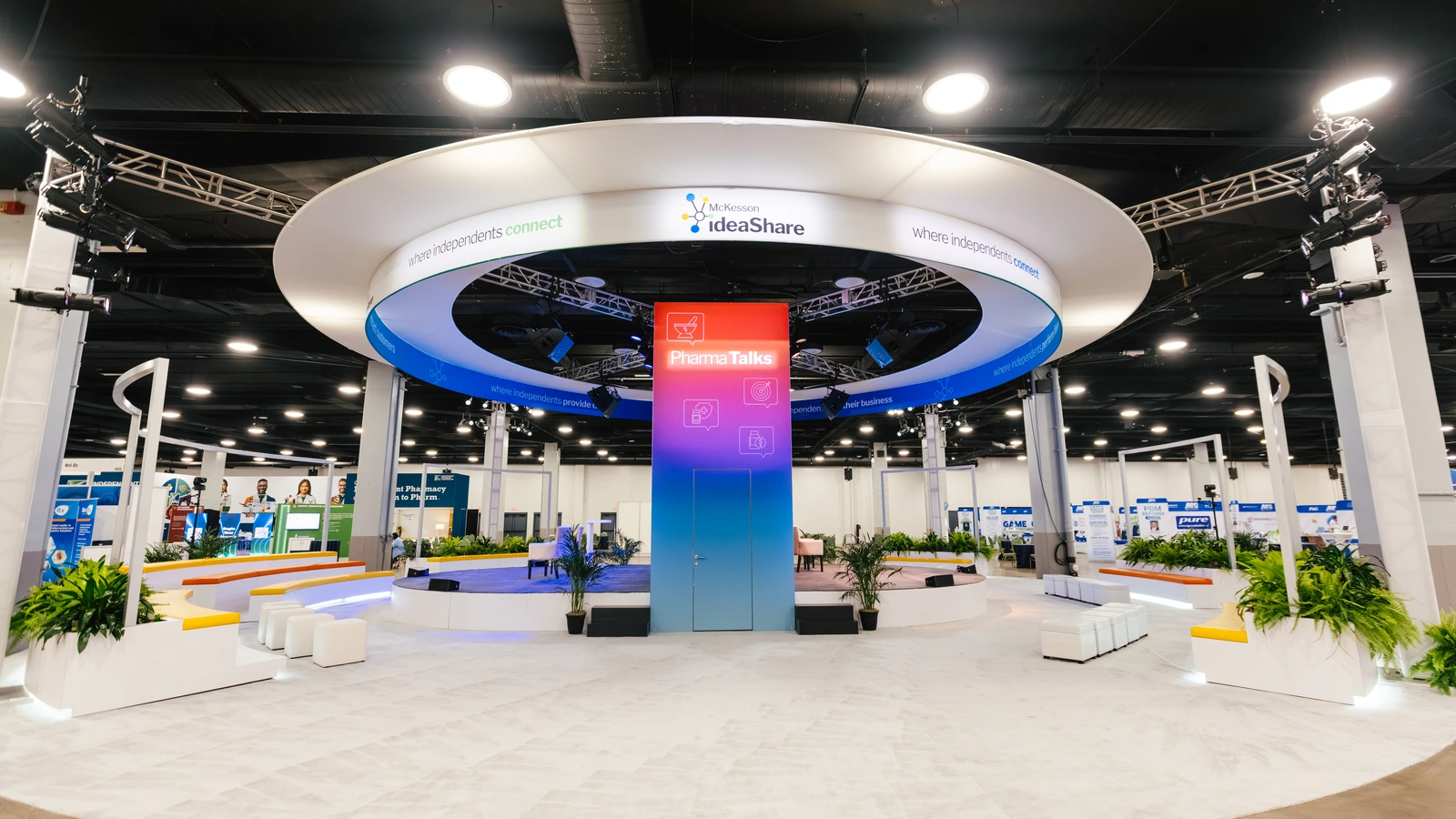 The Sparks-designed circular central theater hub, lit in McKesson purple and pink, on the Main Street USA-themed McKesson ideaShare 2025 tradeshow floor at the Gaylord Opryland Resort & Convention Center in Nashville.
