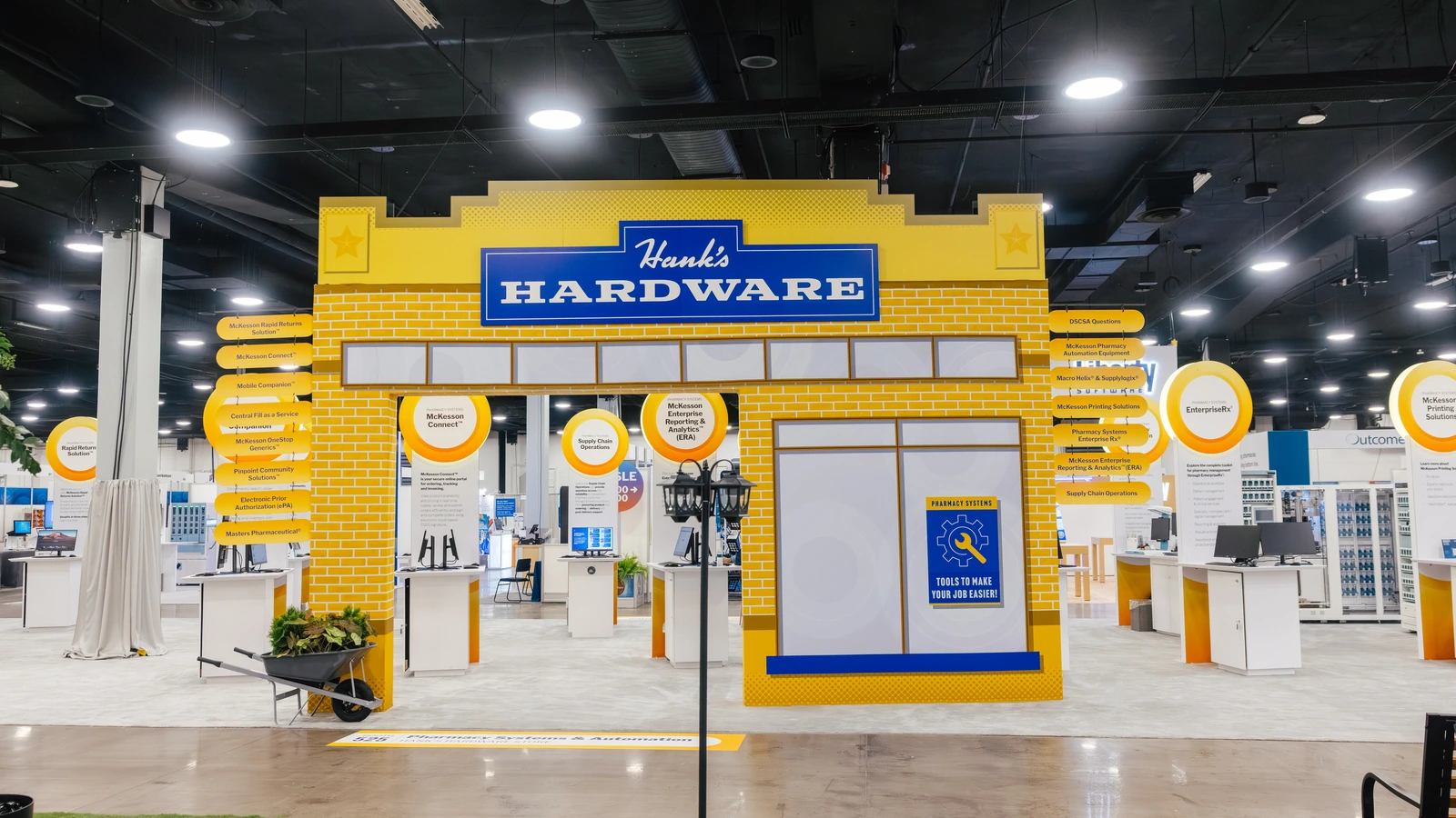 The Sparks-designed Hank's Hardware storefront — a yellow-clapboard facade with vintage signage — on the Main Street USA-themed McKesson ideaShare 2025 tradeshow floor at the Gaylord Opryland Resort & Convention Center in Nashville.