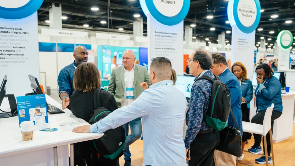 Attendees engage with a McKesson representative at the Sparks-designed MyHealthMart Support consultation area on the Main Street USA-themed McKesson ideaShare 2025 tradeshow floor at the Gaylord Opryland Resort & Convention Center in Nashville.