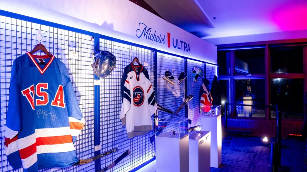 USOPC archive exhibit curated for Sparks-produced Michelob ULTRA Summit at Red Pine Lodge — signed Team USA hockey jerseys, helmets, and Olympic memorabilia from the United States Olympic & Paralympic Committee, celebrating the closing weekend of the Milano Cortina 2026 Winter Olympics.