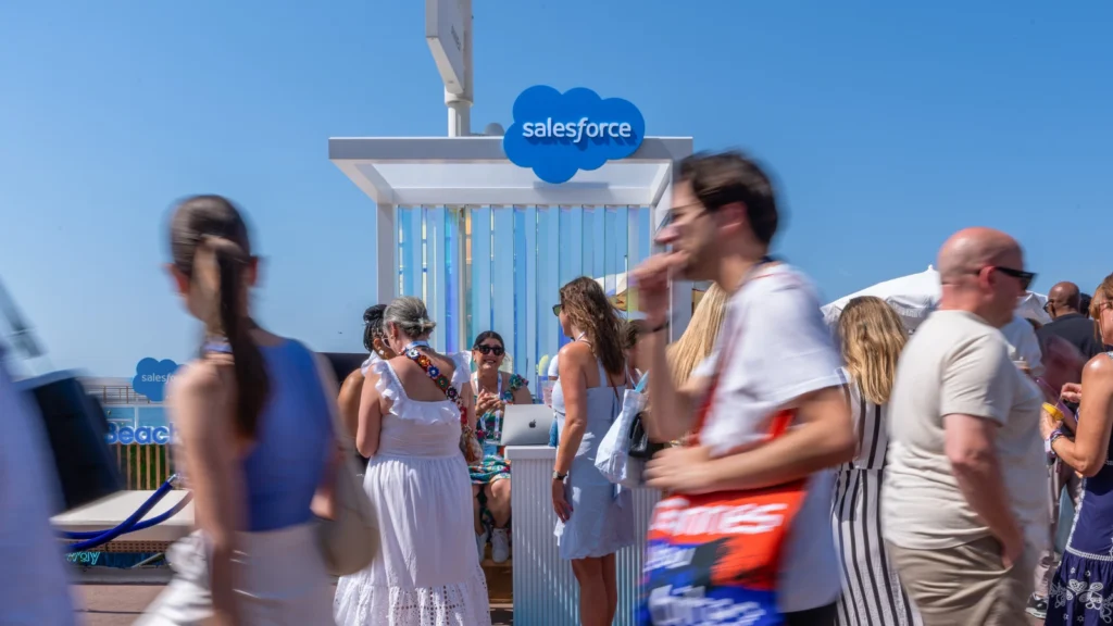 Guests gathered at the Salesforce cloud-logo kiosk with the Salesforce Beach flag flying above the Sparks-designed activation at Cannes Lions 2026 on Annex Beach off La Croisette.