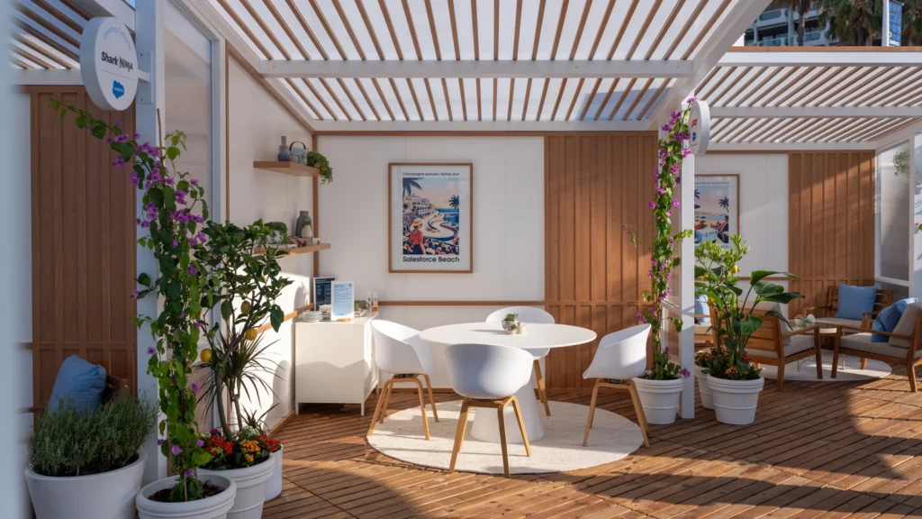 Shark NINJA-branded meeting cabana with white pergola, bougainvillea, and "Champagne sprayed, laptop shut" Salesforce Beach travel poster at the Sparks-designed activation at Cannes Lions 2026.