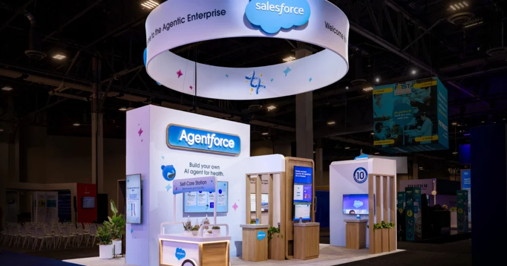 Salesforce booth at HIMSS 2026 featuring the signature cloud-logo halo ring with 'Welcome to the Agentic Enterprise,' Agentforce branded cube signage, 'Build your own AI agent for health' messaging, and a Self-Care Station activation — Sparks-designed environment at the Venetian Convention & Expo Center in Las Vegas.