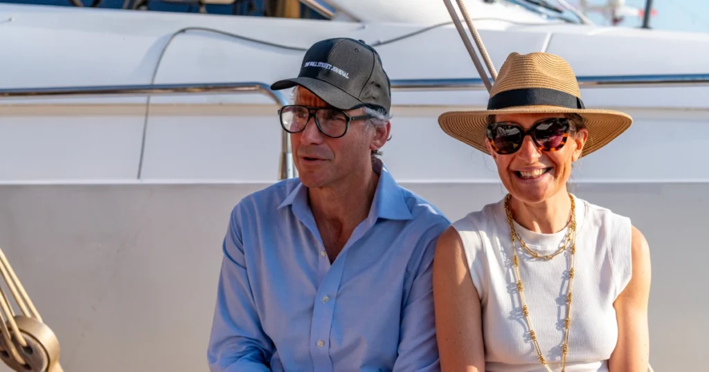 Two VIP guests, one wearing a Wall Street Journal cap, sharing morning coffee on the deck of the O'Remington at the Sparks-produced Riviera at Dawn breakfast cruise for The Wall Street Journal at Cannes Lions 2026.