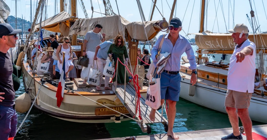 VIP guests disembarking the O'Remington with WSJ-branded tote bags and printed souvenir newspapers at Port Canto at the Sparks-produced Riviera at Dawn for The Wall Street Journal at Cannes Lions 2026.