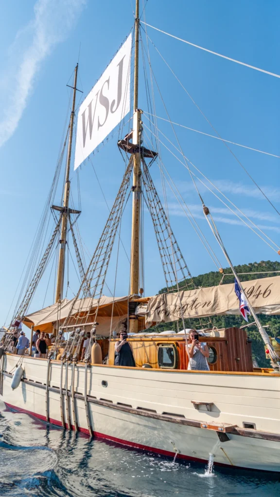 The O'Remington heritage schooner underway with the WSJ-branded sail flying overhead as VIP guests photograph the Côte d'Azur coastline from the deck during the Sparks-produced Riviera at Dawn breakfast cruise for The Wall Street Journal at Cannes Lions 2026.
