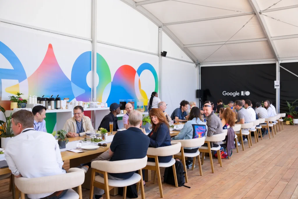 Attendees share lunch and conversation at long tables inside a dining tent