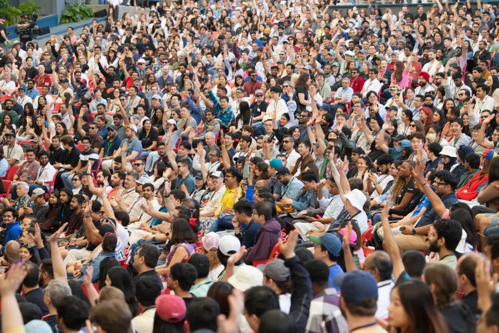 Dense crowd of developers raising their hands during a Google I/O gathering