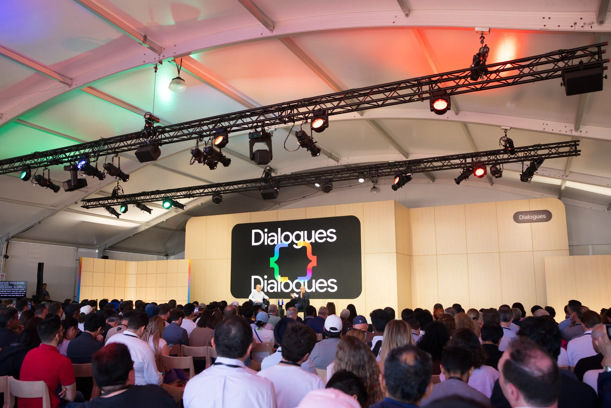 Packed Dialogues stage audience under theatrical truss lighting inside a temporary structure
