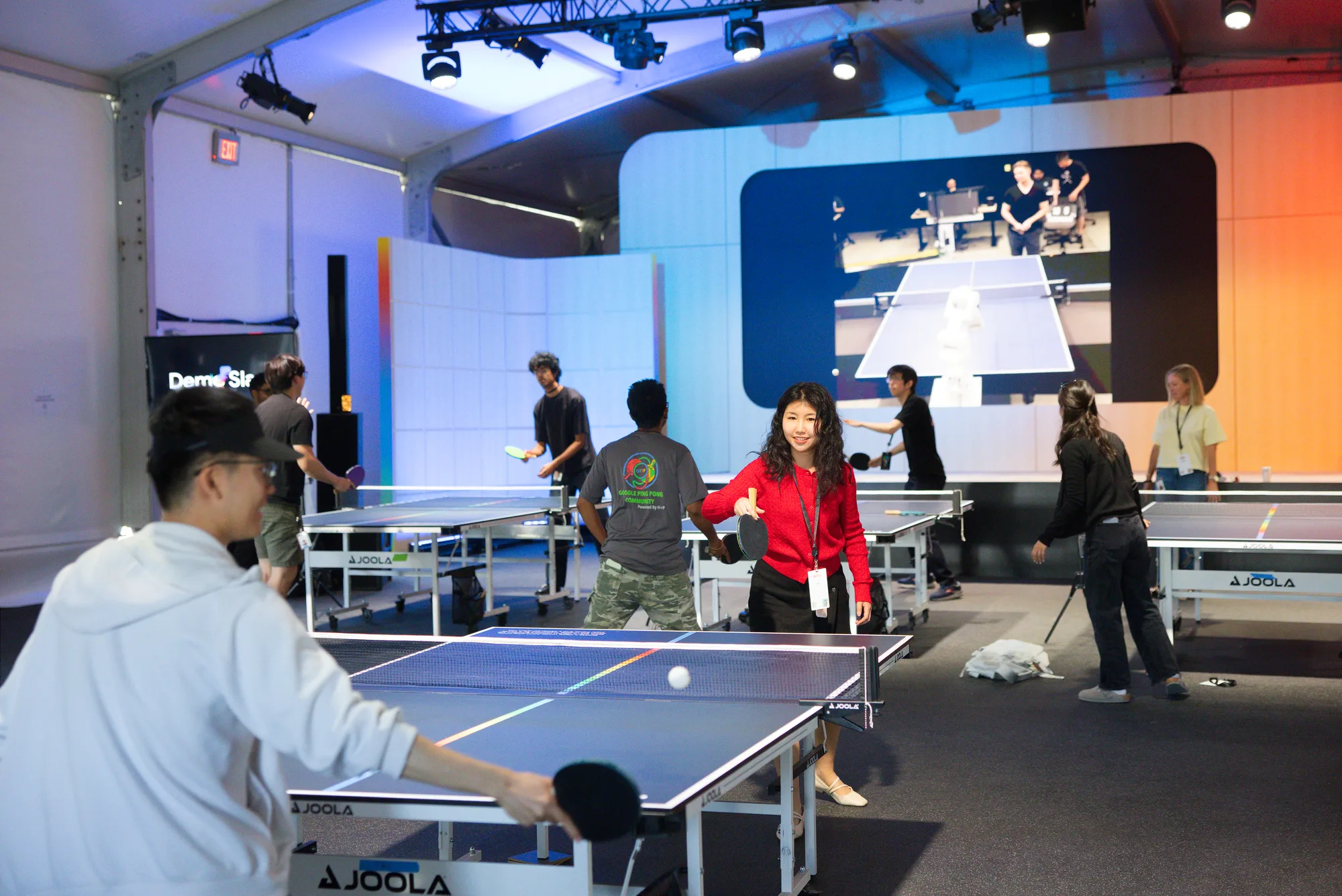 Attendees play ping-pong across several tables during an evening event