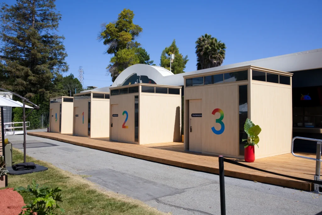 Numbered wood-clad meeting pods on decking Sparks built over an asphalt parking lot