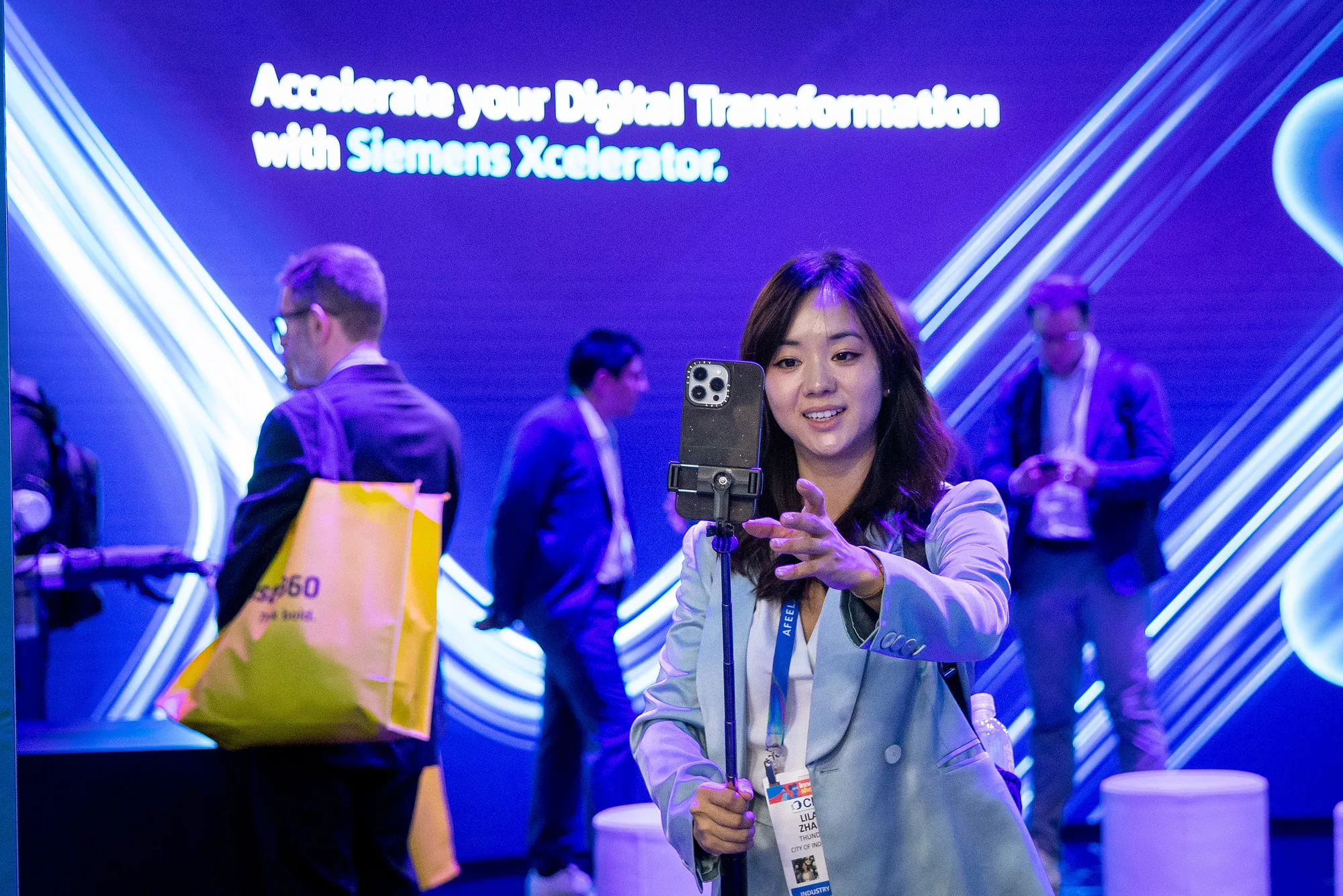 CES 2026 attendee filming with her phone in front of the Siemens Xcelerator LED wall.