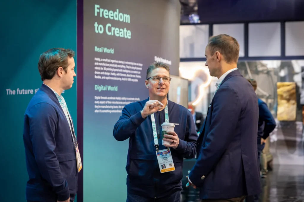 Siemens expert in conversation with two attendees beside Haddy's "Freedom to Create" story panel at CES 2026.