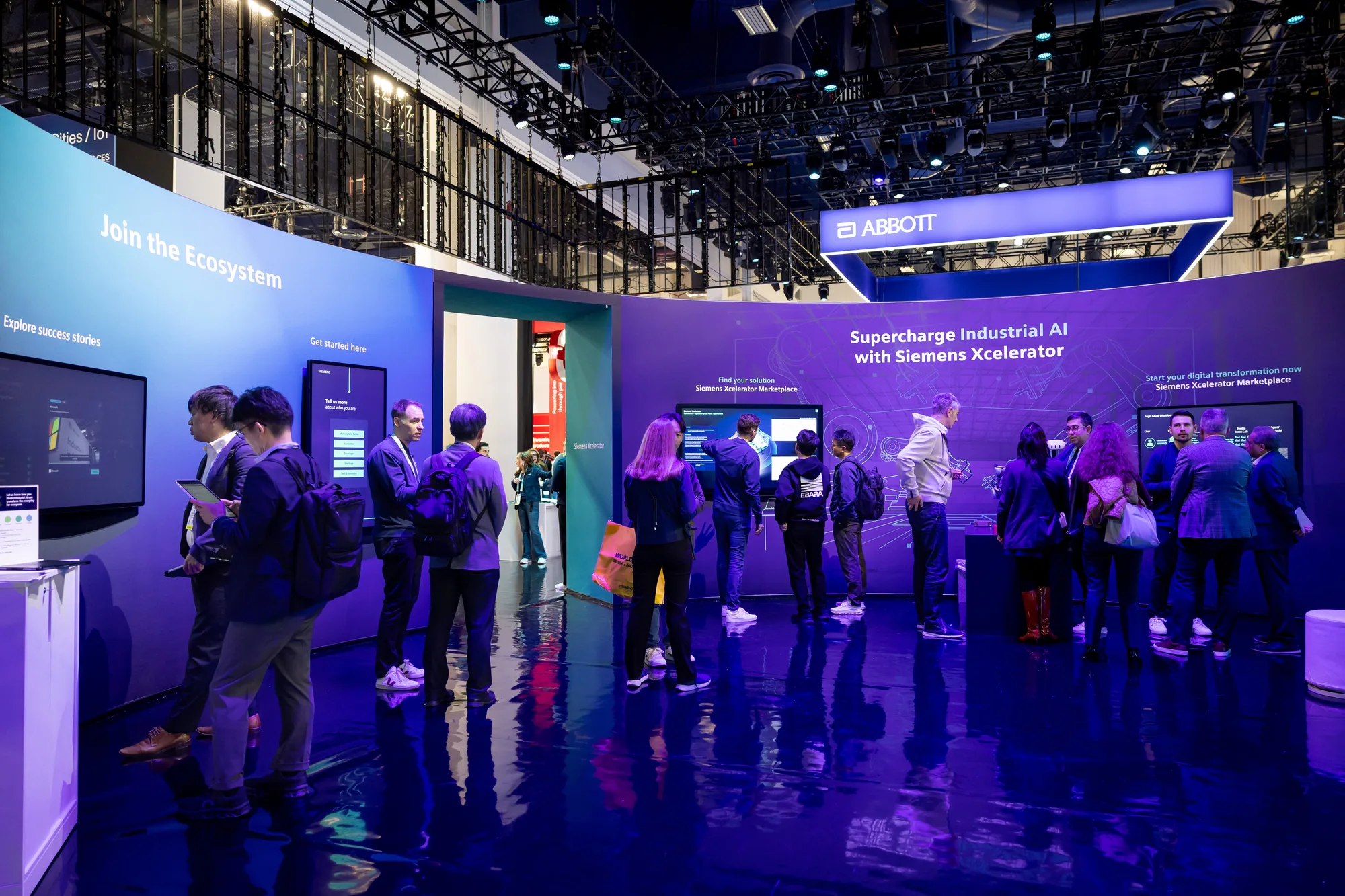 Attendees exploring the "Join the Ecosystem" and "Supercharge Industrial AI" interactive walls inside the Siemens exhibit at CES 2026.
