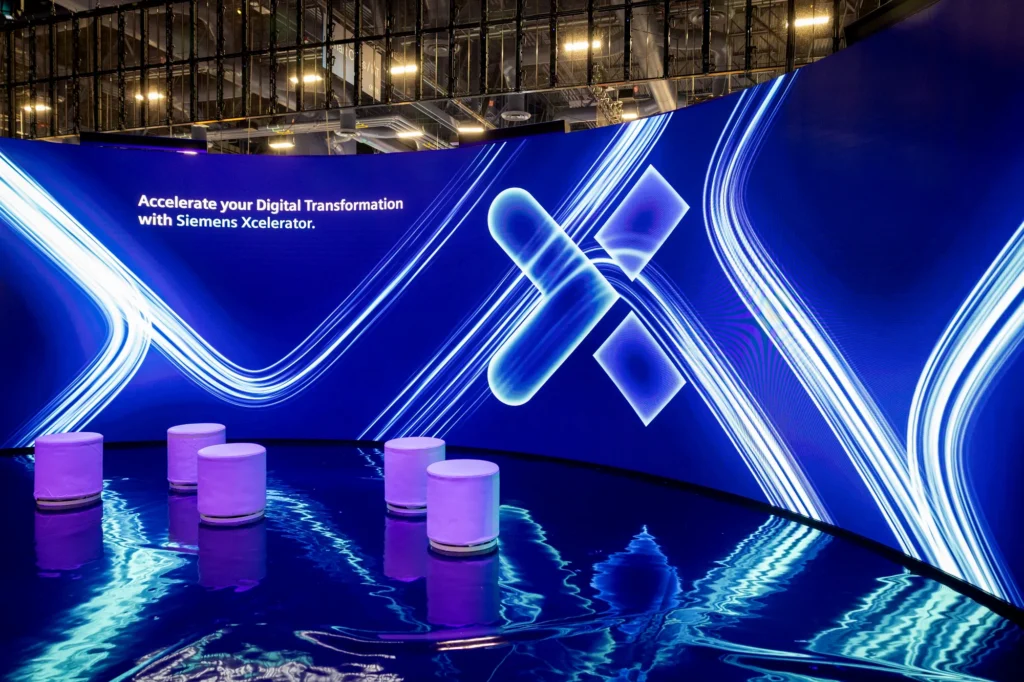 Curved LED screen inside the Siemens Xcelerator environment reading "Accelerate your Digital Transformation with Siemens Xcelerator."