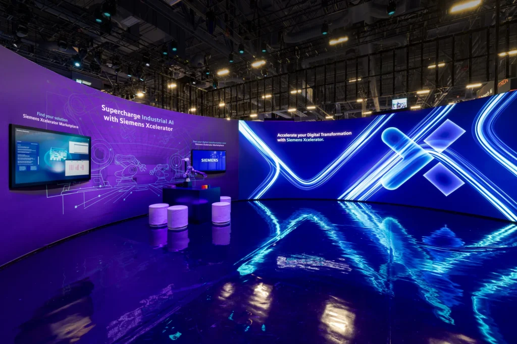 Interior of the Siemens Xcelerator environment at CES 2026, pairing a curved LED wall with Xcelerator Marketplace screens.